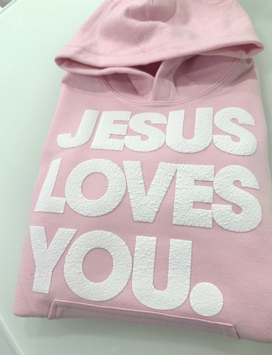 Pink hoodie with 'Jesus Loves You' text on a white background
